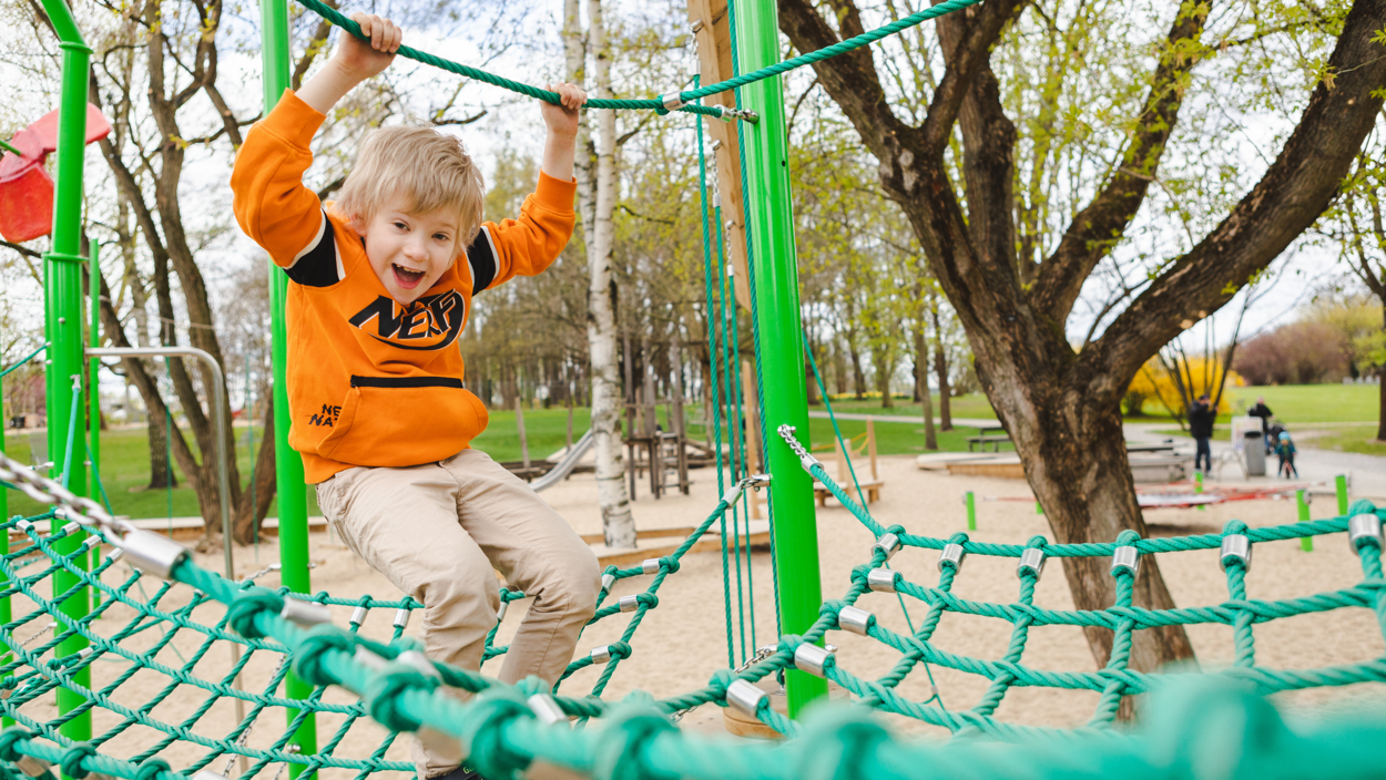 Ein Kind balanciert auf einem schwebenden Netz auf einem Spielplatz in den Gärten der Welt